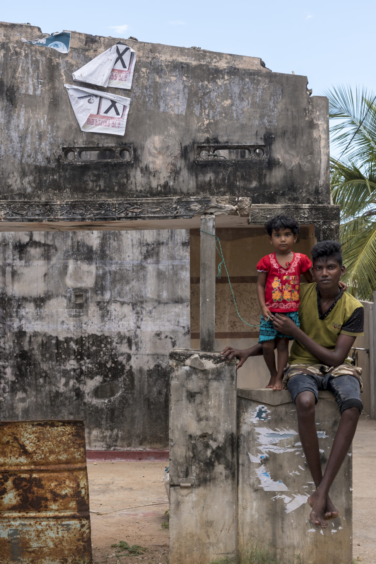 Mann und Kind vor zerstörtem Haus in Jaffna